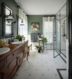 a bathroom with green walls and white tile flooring, two sinks on either side of the bathtub