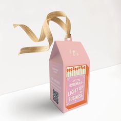 a pink carton with some brown string attached to it that is on top of a white table