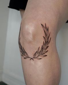 a woman's leg with a tattoo on it that has leaves in the shape of a circle