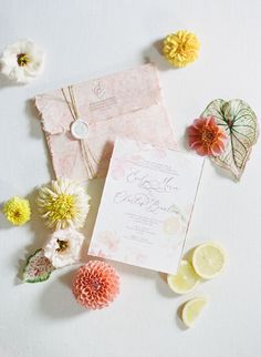 the wedding stationery is laid out with flowers and lemons