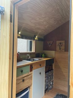 the inside of a tiny house with wood paneling on the walls and cabinets in it