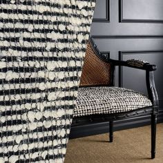 a black and white chair sitting in front of a wall with a checkered blanket on it