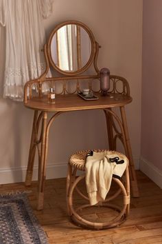 a small wooden table with a mirror on top of it next to a rug and window