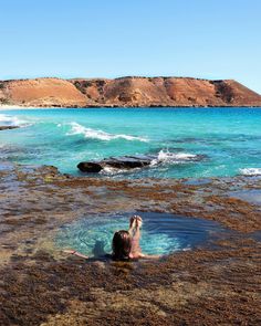 a woman is swimming in the ocean with her feet up and arms out to the water