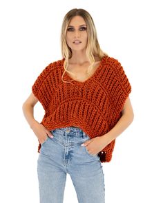 a woman wearing an orange sweater and jeans is standing in front of a white background