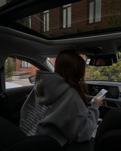 a woman sitting in the driver's seat of a car holding a remote control