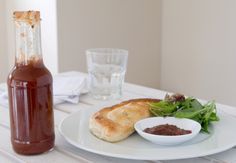 a bottle of ketchup sitting on top of a table next to a plate with food