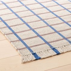 a blue and white rug with fringes on top of wooden floor next to wood flooring