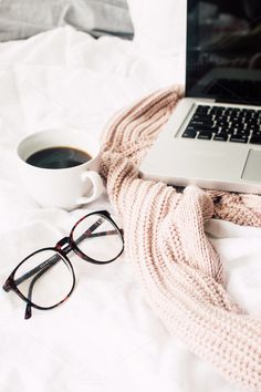 an open laptop computer sitting on top of a bed next to a cup of coffee