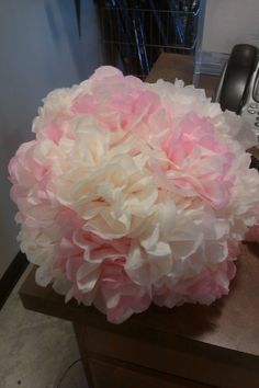 a large pink and white flower sitting on top of a wooden table next to a phone