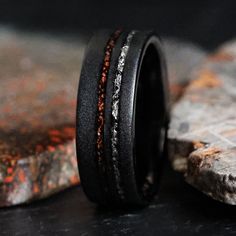 a black wedding band with red and white stones inlayed to the inside of it