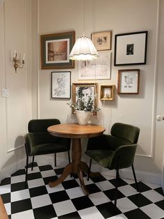 two green chairs sitting at a round table in a room with black and white checkered flooring