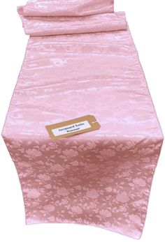 a pink table cloth with a gold label on the front and back of it's cover