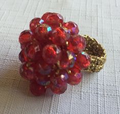 "Red 60s or 70s Big Ring with a band made of gold Stretchy fabric, so it's one size fits all. The ring is basically a 1\" mound of Ruby Red Faceted plastic stones, woven into a shiny red mound. Also, please take a look at my storefront at: https://www.etsy.com/shop/FabFinds42?ref=seller-platform-mcnav I have a wide selection of one-of-a-kind items, from clothing and toys to home decor and gift items, and I add new things almost every day." Round Red Ruby Party Ring, Party Ruby Ring With Round Shape, Vintage Adjustable Red Ruby Ring, Adjustable Vintage Ruby Ring, Party Ruby Ring, Handmade Adjustable Red Ruby Ring, Hippie Ring, Stretchy Rings, Shiny Rings