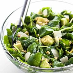 a salad with spinach and cheese in a glass bowl