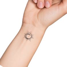 a woman's arm with a small sun and moon tattoo on the left wrist