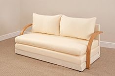 a white couch with two pillows on it in a living room next to a wall