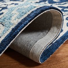 a blue and white rug on the floor with a wooden floor in front of it