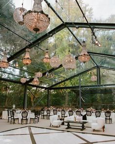 an indoor dining area with chandeliers hanging from the ceiling and tables set for dinner