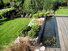 an outdoor garden with water feature and wooden decking