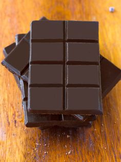 three pieces of chocolate sitting on top of each other in front of a wooden table