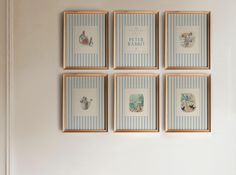 four framed pictures hang on the wall above a toilet in a room with blue and white striped walls