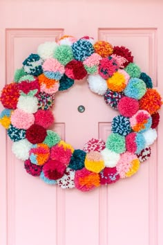 a pink door with a colorful wreath on it