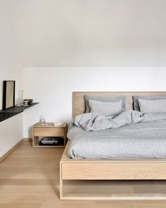 a large bed sitting next to a wooden night stand on top of a hard wood floor