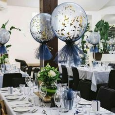 the table is set with silver and white decorations for an event or celebration, while balloons are floating in the air