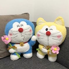 two stuffed animals sitting on top of a couch next to each other with flowers in their hands