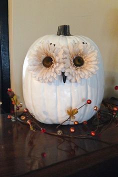 a white pumpkin decorated with flowers and an owl