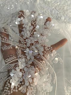 the bridal bouquet is adorned with pearls and sequins, along with sheer netting