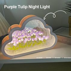 purple tulips are placed in the shape of a cloud on a table next to a potted plant