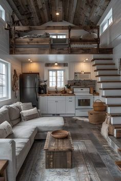 a living room filled with furniture next to a kitchen and stairway leading up to the loft