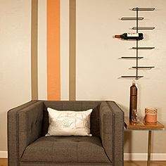 a living room with a chair, table and wine rack on the wall next to it