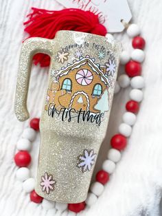 a christmas mug with a gingerbread house on it and red tassels around it