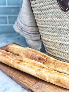 two breadsticks sitting on top of a wooden cutting board next to a basket