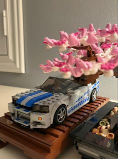 a toy car is parked next to a tree with pink and white flowers on it