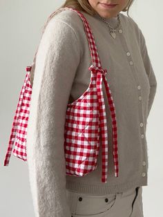 a woman wearing a red and white gingham bag with her hands in her pockets