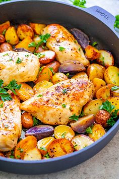 chicken, potatoes and carrots in a pan with parsley on the side for garnish