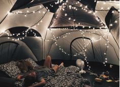 a person laying in a bed inside of a tent with lights on the ceiling and walls