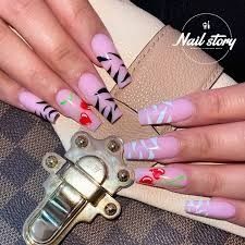 a woman with pink and black nail designs on her nails holding a pair of scissors