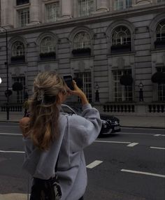 a woman standing on the side of a road taking a photo