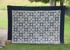 a blue and white quilt hanging from a tree