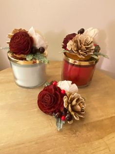 two tins with flowers and pine cones in them