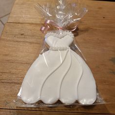 a wedding dress shaped cookie in plastic on a wooden table