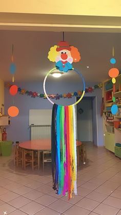 there is a rainbow decoration in the middle of this room with balloons and streamers hanging from the ceiling