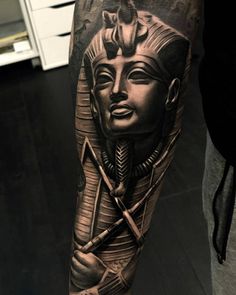 a man's arm with an egyptian mask and two crossed swords on the forearm