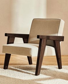 a chair sitting on top of a wooden floor next to a white rug and wall