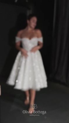 a woman in a white dress is walking down the runway